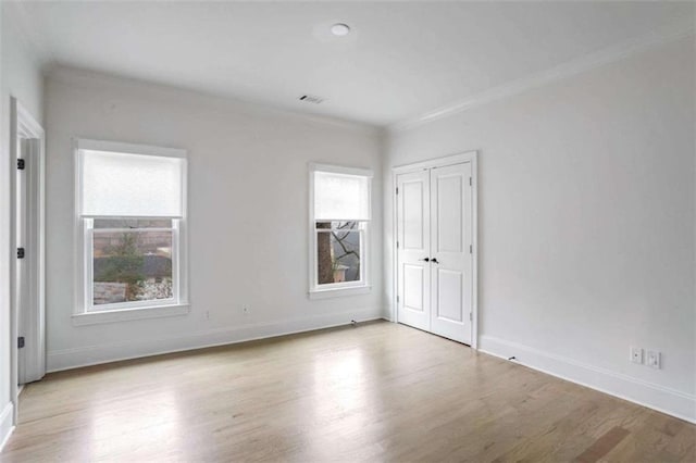 empty room with ornamental molding and light hardwood / wood-style floors