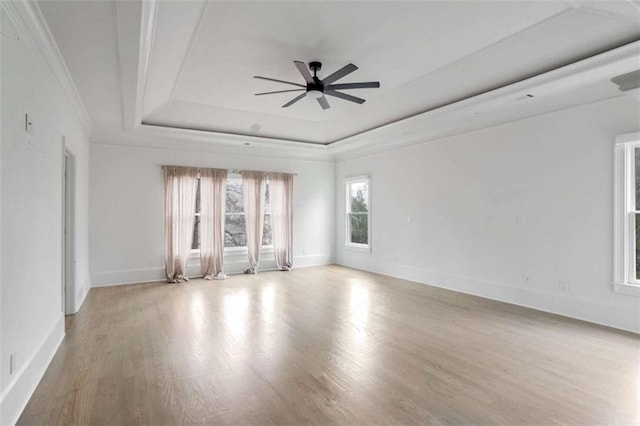 empty room featuring ornamental molding, light hardwood / wood-style flooring, ceiling fan, and a tray ceiling