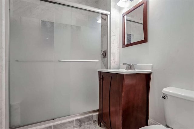 bathroom with toilet, vanity, and a shower with shower door