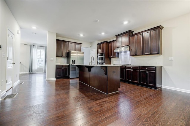 kitchen with appliances with stainless steel finishes, under cabinet range hood, baseboards, dark wood-style floors, and dark brown cabinets