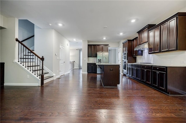 kitchen with dark wood-type flooring, dark brown cabinets, appliances with stainless steel finishes, baseboards, and recessed lighting