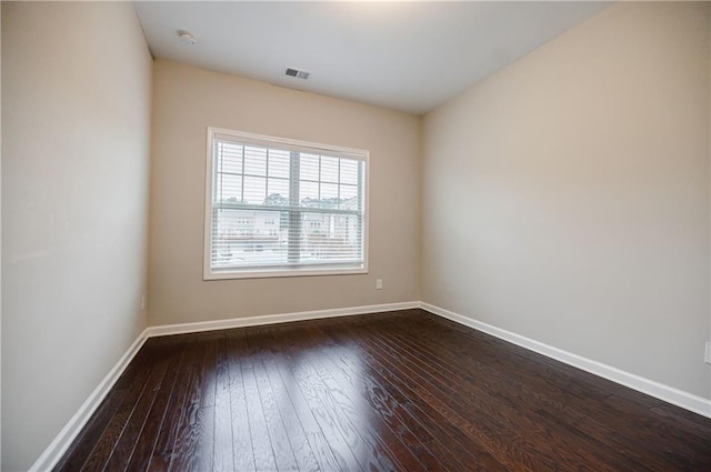 spare room featuring dark wood-type flooring and baseboards