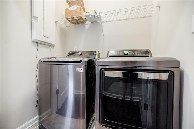 laundry room with washer and clothes dryer, baseboards, and electric panel