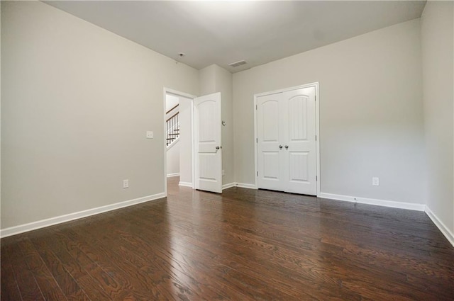 unfurnished bedroom with dark wood-style flooring and baseboards