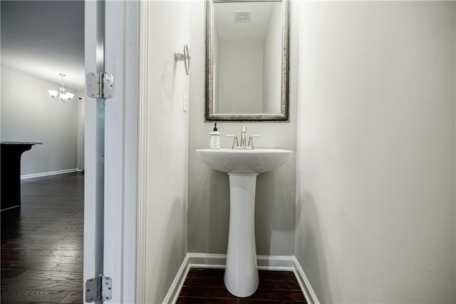 bathroom with baseboards, wood finished floors, and a chandelier
