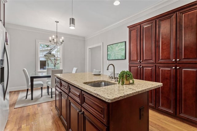 kitchen with an inviting chandelier, sink, an island with sink, and light hardwood / wood-style floors