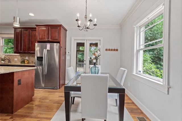 dining area featuring a wealth of natural light, light hardwood / wood-style flooring, and an inviting chandelier