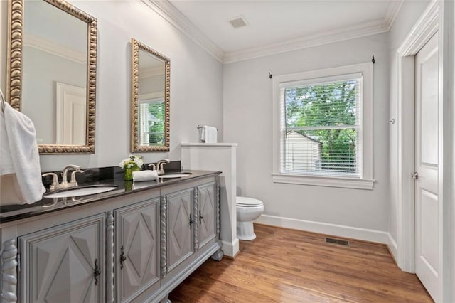 bathroom featuring dual sinks, toilet, hardwood / wood-style flooring, and a healthy amount of sunlight