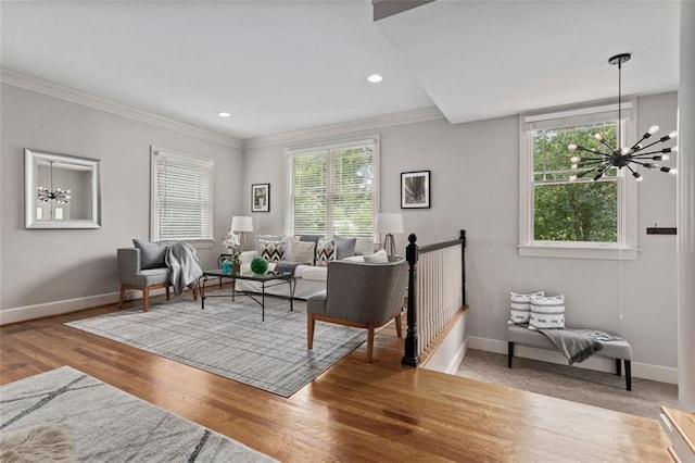 sitting room with a notable chandelier, light hardwood / wood-style flooring, ornamental molding, and plenty of natural light