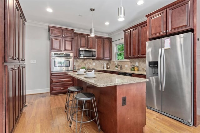 kitchen featuring a kitchen island, light hardwood / wood-style flooring, appliances with stainless steel finishes, backsplash, and hanging light fixtures