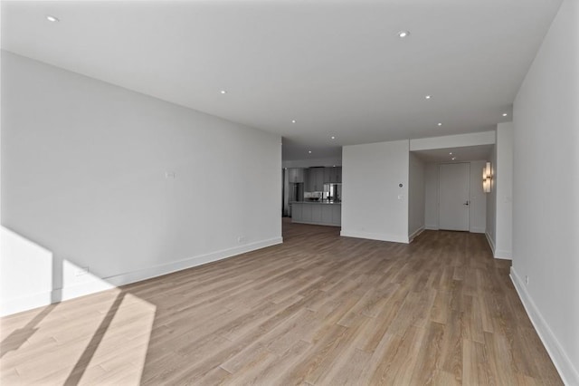 unfurnished living room featuring recessed lighting, light wood-style flooring, and baseboards