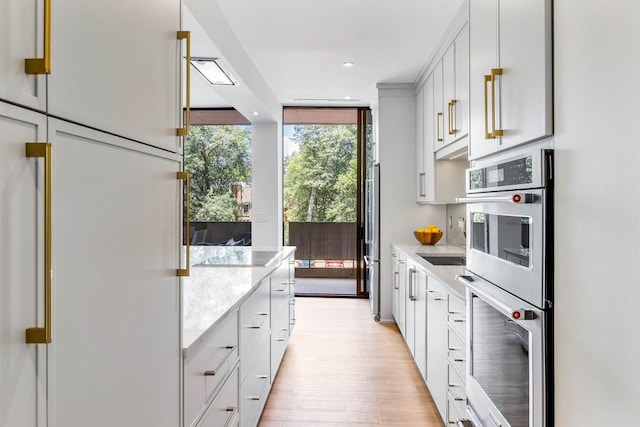 kitchen with a wall of windows, light countertops, recessed lighting, light wood-style flooring, and stainless steel double oven