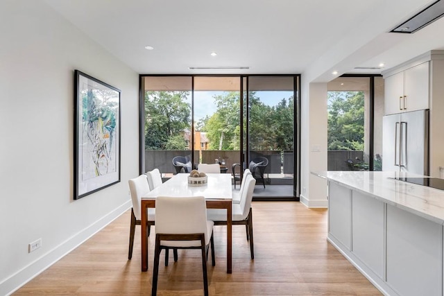 dining space with floor to ceiling windows, recessed lighting, light wood-style floors, and baseboards