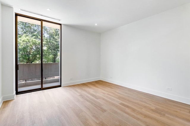 spare room featuring baseboards, wood finished floors, and floor to ceiling windows