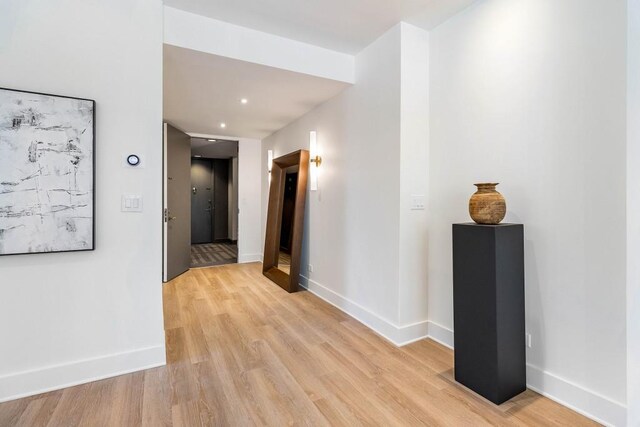 empty room featuring a wall of windows, baseboards, and wood finished floors