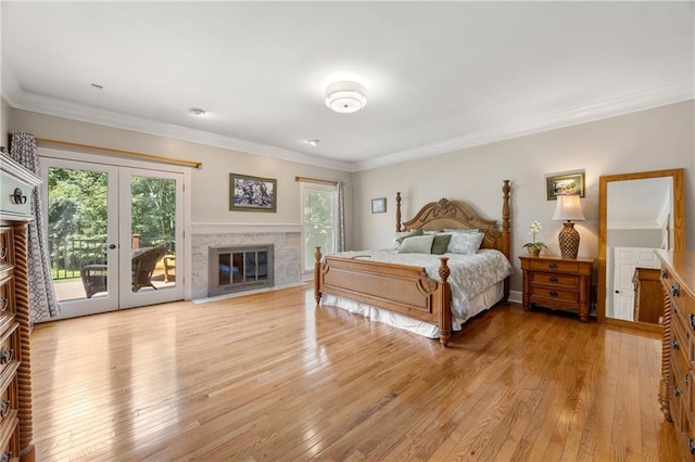 bedroom with french doors, crown molding, light wood-type flooring, a fireplace, and access to exterior