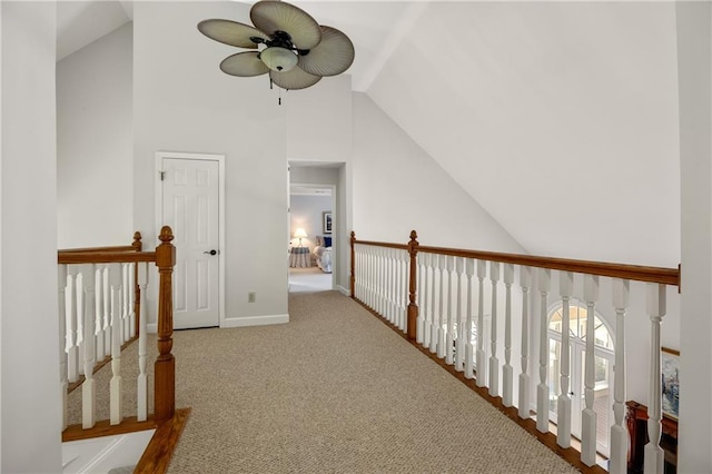 hallway with high vaulted ceiling and light colored carpet