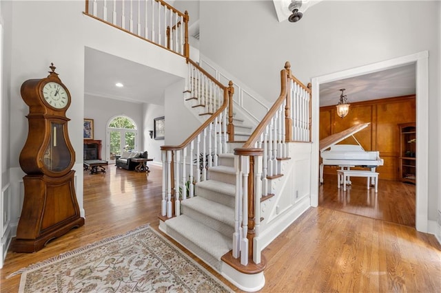 staircase with a towering ceiling, ornamental molding, and wood-type flooring