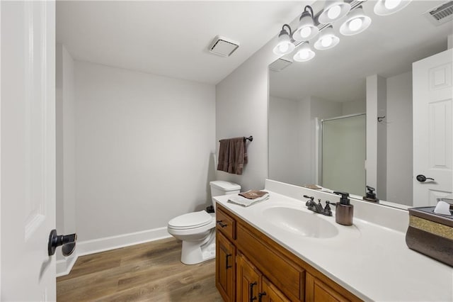 bathroom featuring toilet, hardwood / wood-style flooring, walk in shower, and vanity