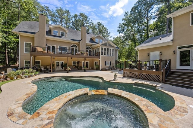 rear view of property with a patio area, french doors, and a swimming pool with hot tub