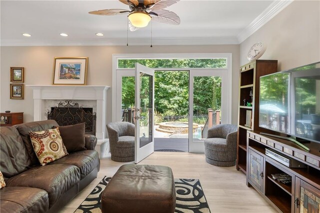 living room featuring a fireplace, light hardwood / wood-style floors, a healthy amount of sunlight, and ornamental molding