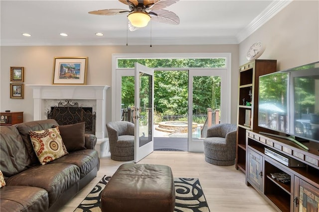 living room with ceiling fan, a high end fireplace, ornamental molding, and light wood-type flooring