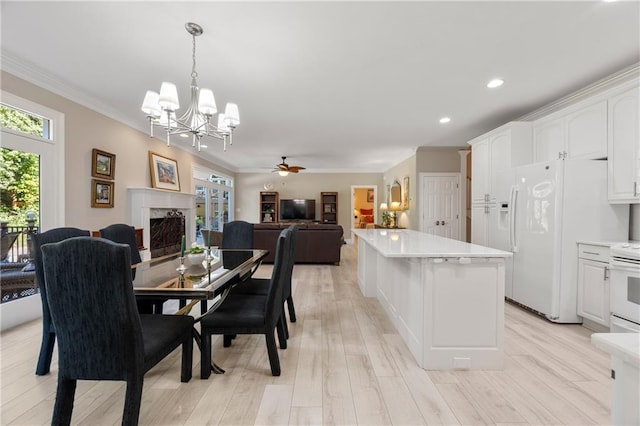 dining room featuring a high end fireplace, crown molding, light hardwood / wood-style floors, and ceiling fan with notable chandelier