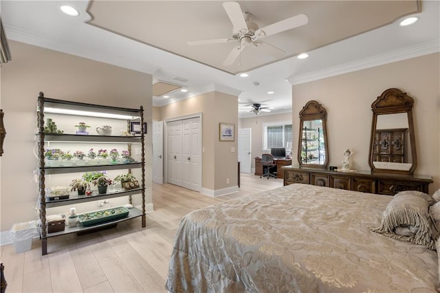 bedroom featuring ceiling fan, ornamental molding, light wood-type flooring, and a closet