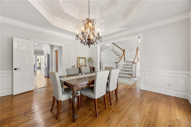 dining area with hardwood / wood-style floors, a tray ceiling, and ornamental molding