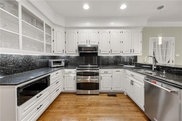 kitchen with white cabinetry, stainless steel appliances, sink, dark stone countertops, and crown molding