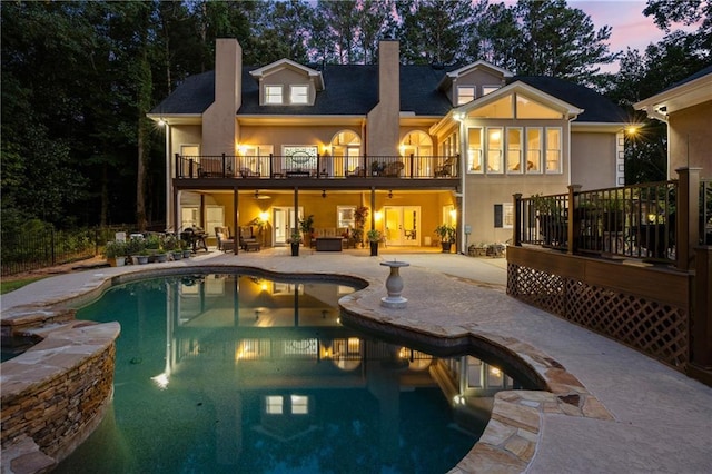 back house at dusk featuring a patio, ceiling fan, and a balcony