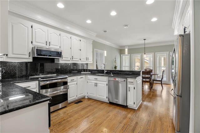 kitchen featuring kitchen peninsula, stainless steel appliances, pendant lighting, and light hardwood / wood-style floors