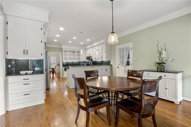 dining space with light hardwood / wood-style floors and ornamental molding