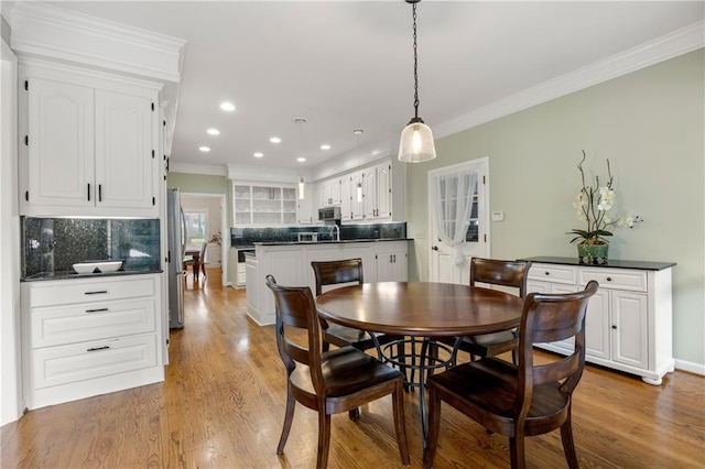 dining space featuring light hardwood / wood-style flooring and crown molding