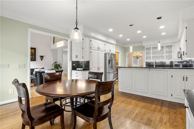 dining space featuring sink, crown molding, light hardwood / wood-style floors, and a chandelier