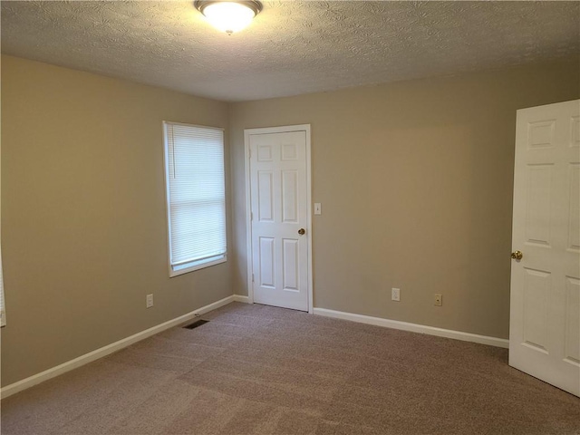 unfurnished room featuring baseboards, carpet floors, a textured ceiling, and visible vents