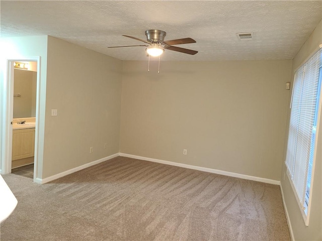 unfurnished room featuring baseboards, carpet flooring, a textured ceiling, and visible vents