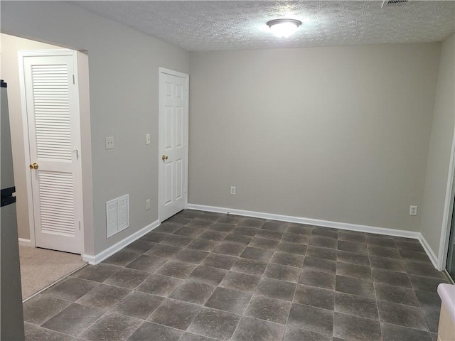 unfurnished room with visible vents, a textured ceiling, and baseboards