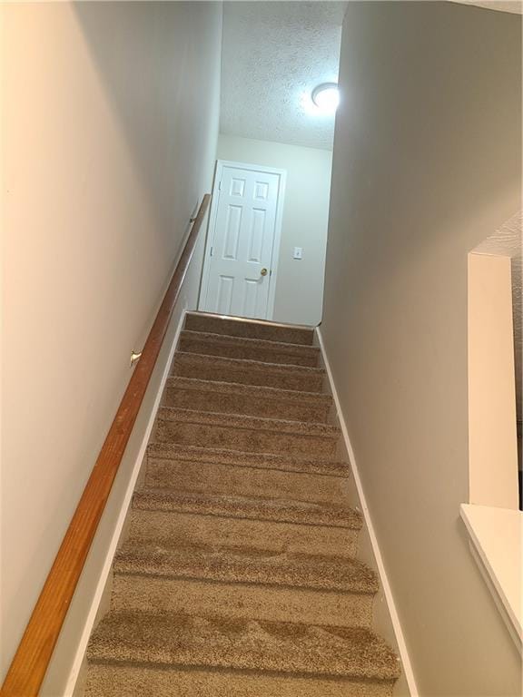 stairway featuring a textured ceiling and baseboards