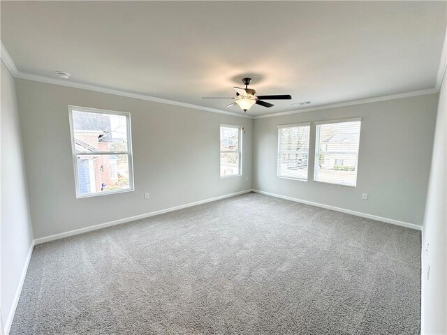 carpeted empty room with visible vents, ceiling fan, baseboards, and ornamental molding