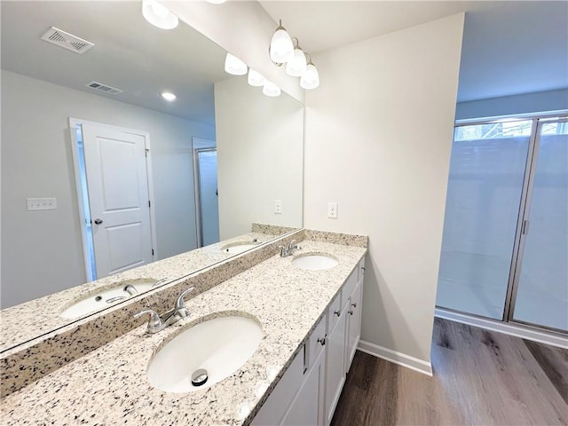 full bathroom with a sink, visible vents, wood finished floors, and double vanity