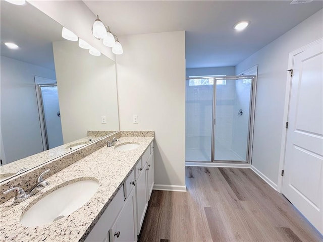 full bath featuring double vanity, a stall shower, wood finished floors, and a sink