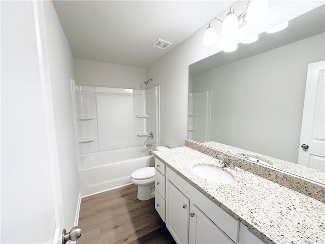 bathroom featuring visible vents, toilet, wood finished floors, shower / bathing tub combination, and vanity