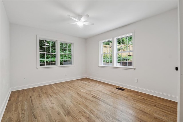 unfurnished room featuring baseboards, light wood-type flooring, visible vents, and a ceiling fan