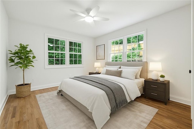 bedroom with a ceiling fan, wood finished floors, and baseboards