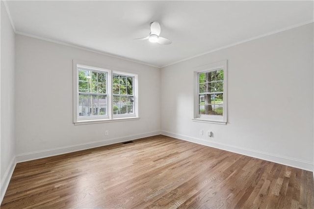 unfurnished room featuring ornamental molding, a wealth of natural light, and wood finished floors