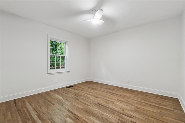 spare room featuring baseboards, visible vents, wood finished floors, and a ceiling fan