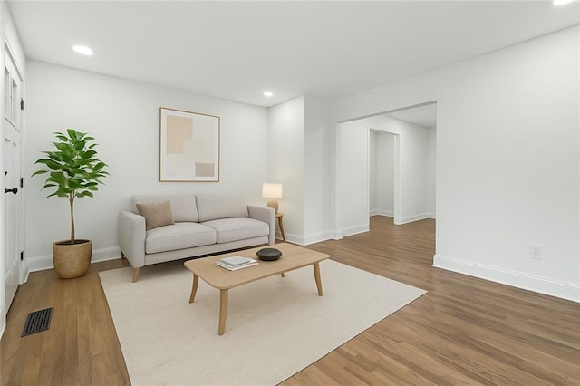 living room with recessed lighting, visible vents, wood finished floors, and baseboards