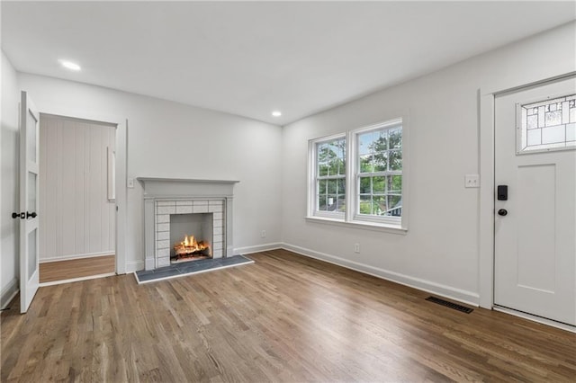 unfurnished living room with a wealth of natural light, visible vents, wood finished floors, and baseboards