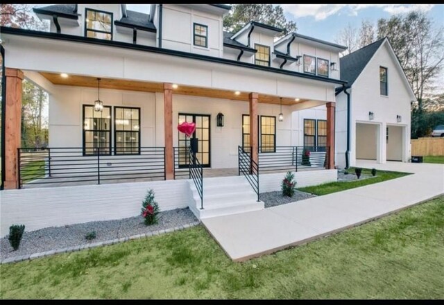 view of front of home featuring a porch, a garage, and a front lawn